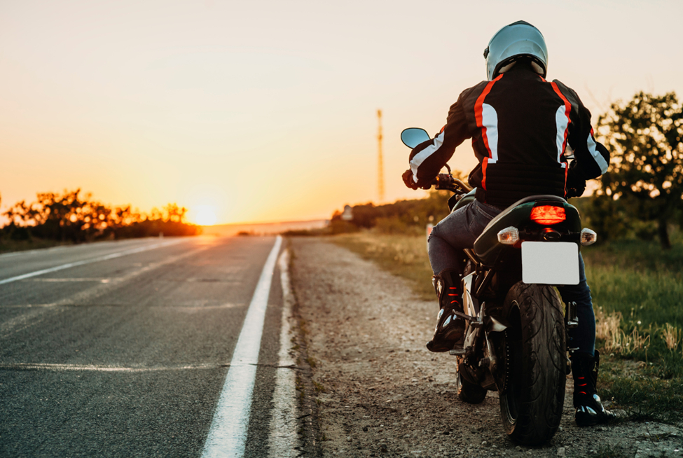A man parked at the side of the road on his motorcycle