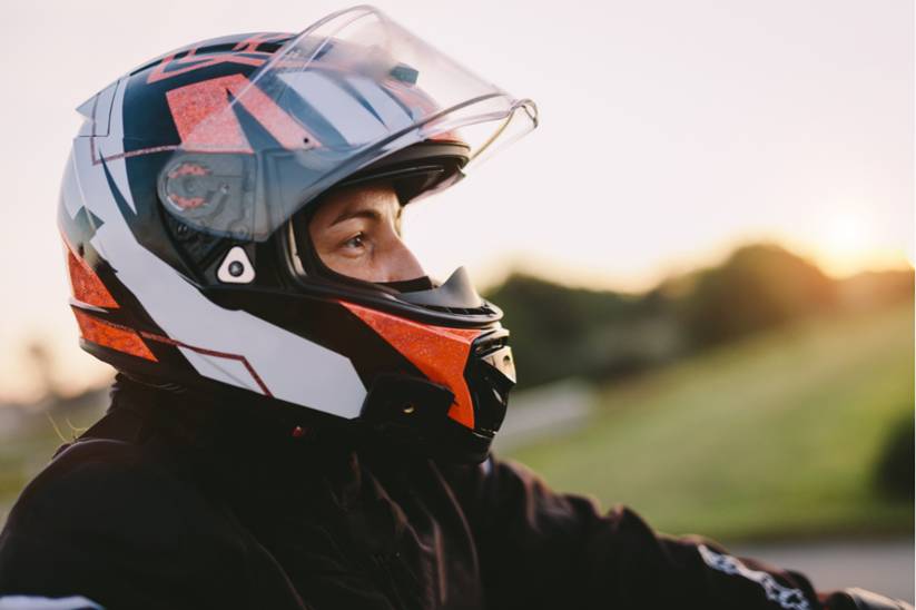 A man in a motorcycle helmet gazing out onto the open road