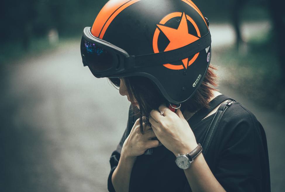 A woman adjusting her motorcycle helmet