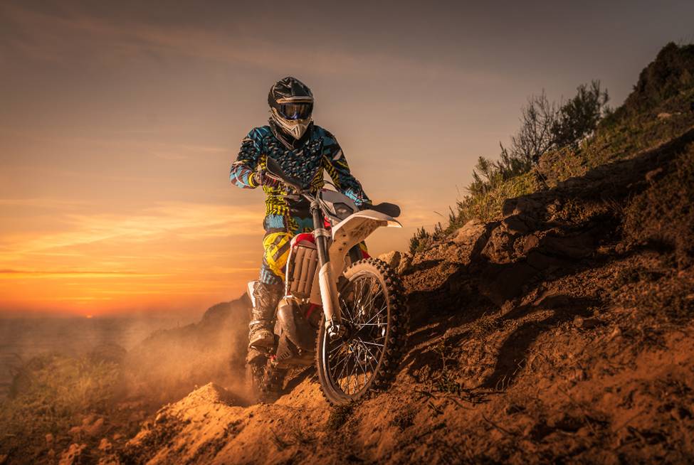 Enduro rider climbing a high slope against a beautiful sunset